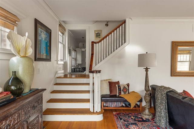 staircase with hardwood / wood-style floors and crown molding