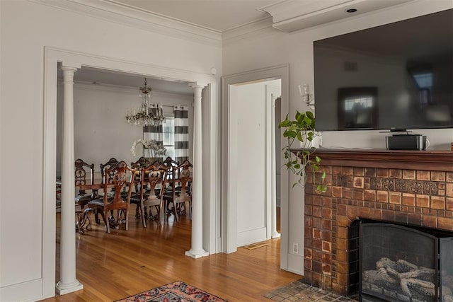 living room featuring decorative columns, ornamental molding, wood-type flooring, and a fireplace