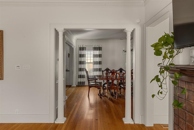 corridor featuring ornate columns, wood-type flooring, and ornamental molding