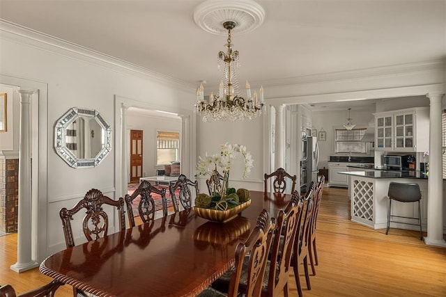 dining area featuring crown molding, hardwood / wood-style floors, and ornate columns