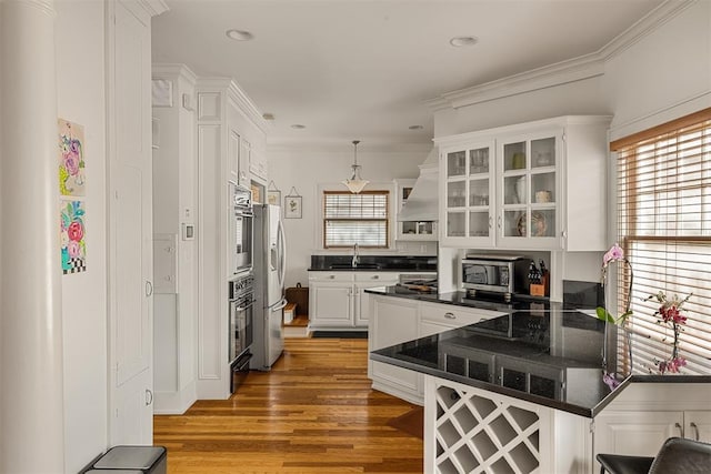 kitchen featuring pendant lighting, white cabinetry, kitchen peninsula, stainless steel appliances, and a healthy amount of sunlight