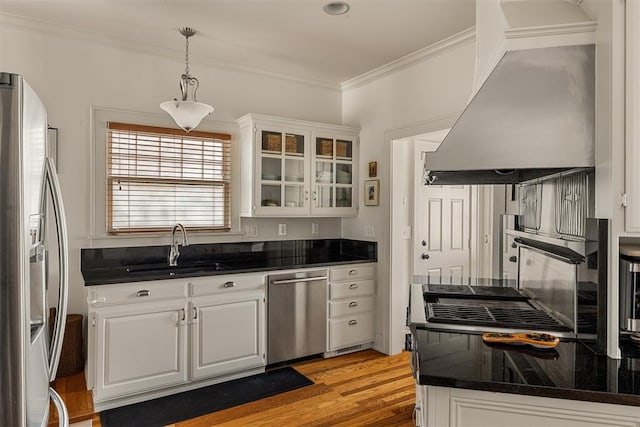 kitchen with extractor fan, appliances with stainless steel finishes, pendant lighting, sink, and white cabinets