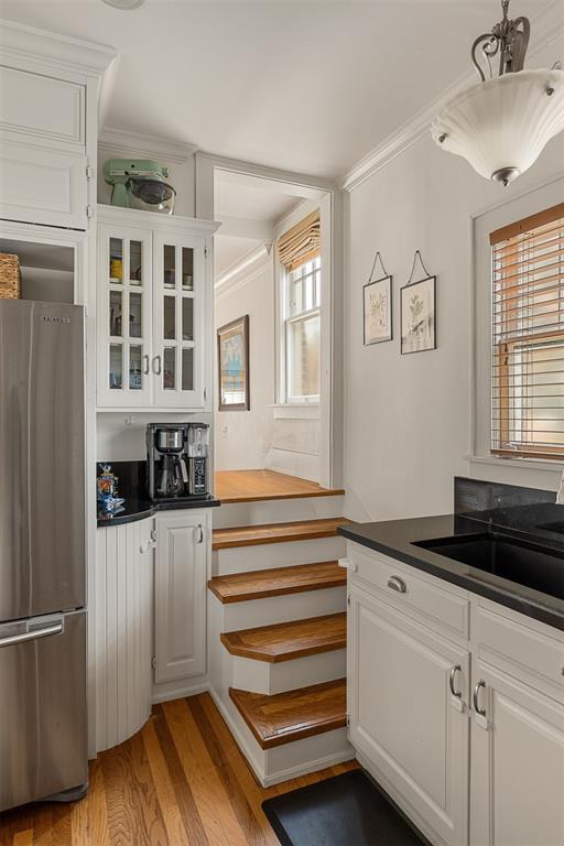 kitchen with stainless steel refrigerator, white cabinetry, crown molding, and light hardwood / wood-style floors