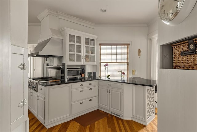 kitchen featuring stainless steel appliances, ornamental molding, white cabinets, and kitchen peninsula