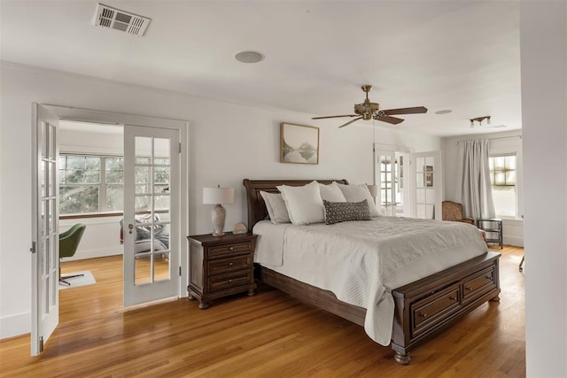 bedroom with wood-type flooring, ceiling fan, and french doors