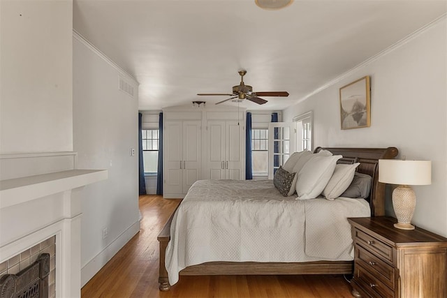 bedroom featuring dark hardwood / wood-style flooring, crown molding, ceiling fan, and a closet