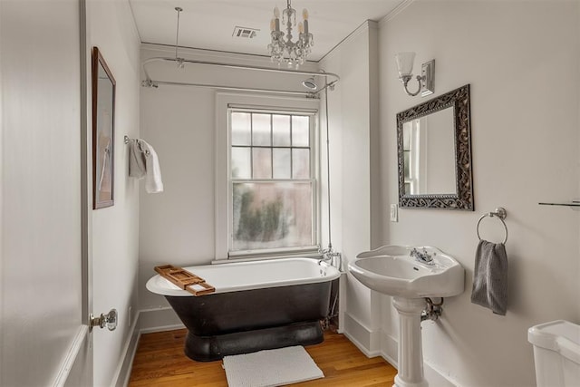 bathroom featuring hardwood / wood-style flooring, crown molding, toilet, and a tub to relax in