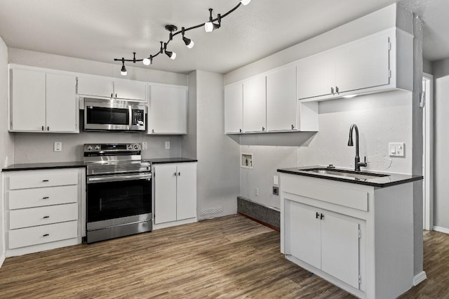 kitchen with dark wood-type flooring, appliances with stainless steel finishes, white cabinetry, and sink