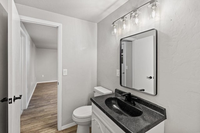 bathroom featuring wood-type flooring, toilet, and vanity