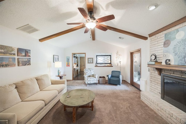 living room with ceiling fan, light colored carpet, a brick fireplace, a textured ceiling, and vaulted ceiling with beams