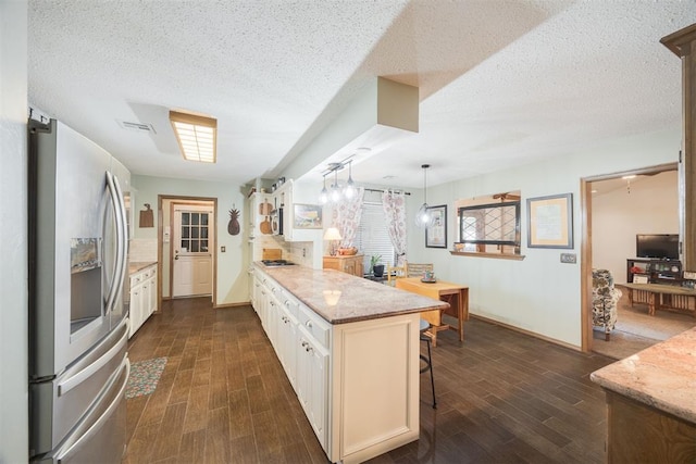 kitchen featuring white cabinets, appliances with stainless steel finishes, a kitchen bar, hanging light fixtures, and kitchen peninsula