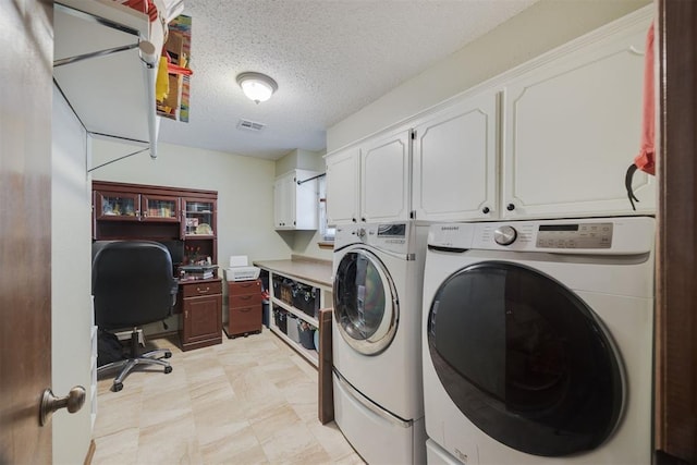 washroom with washer and clothes dryer, a textured ceiling, and cabinets