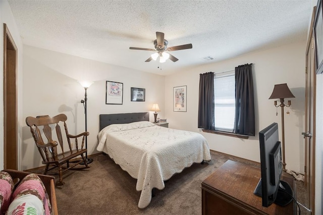 bedroom featuring ceiling fan, dark carpet, and a textured ceiling