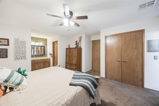 carpeted bedroom with ceiling fan, a textured ceiling, and ensuite bathroom