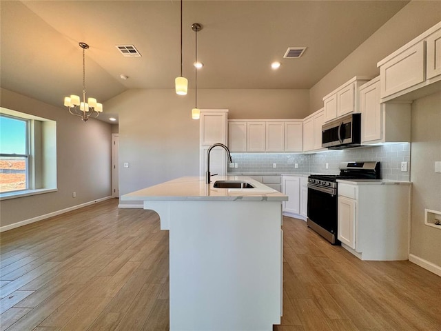 kitchen featuring light wood-type flooring, a sink, stainless steel appliances, light countertops, and decorative backsplash