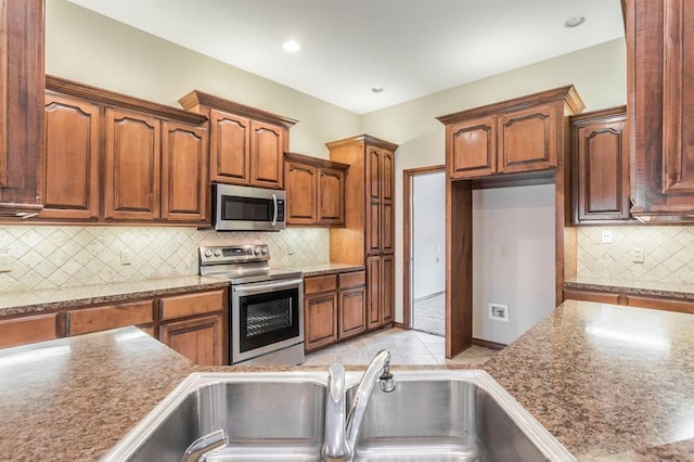 kitchen with light tile patterned floors, appliances with stainless steel finishes, sink, and backsplash