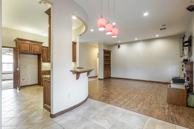 kitchen with light stone counters, a breakfast bar, light tile patterned flooring, and hanging light fixtures