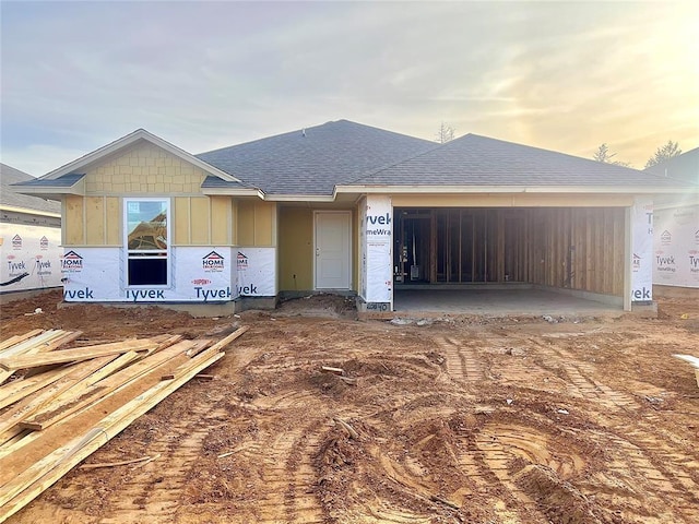 property under construction featuring an attached garage and a shingled roof