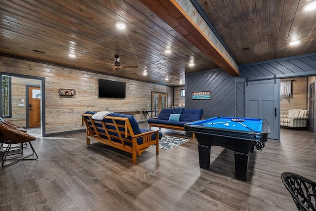 rec room with wood-type flooring, beamed ceiling, wooden walls, ceiling fan, and a barn door