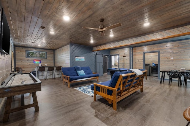 playroom with a barn door, hardwood / wood-style floors, washing machine and dryer, wooden walls, and wooden ceiling