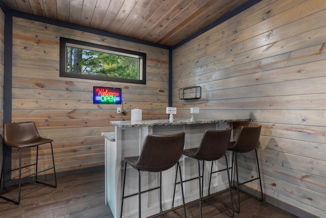 bar with light stone counters, wood walls, and wood ceiling