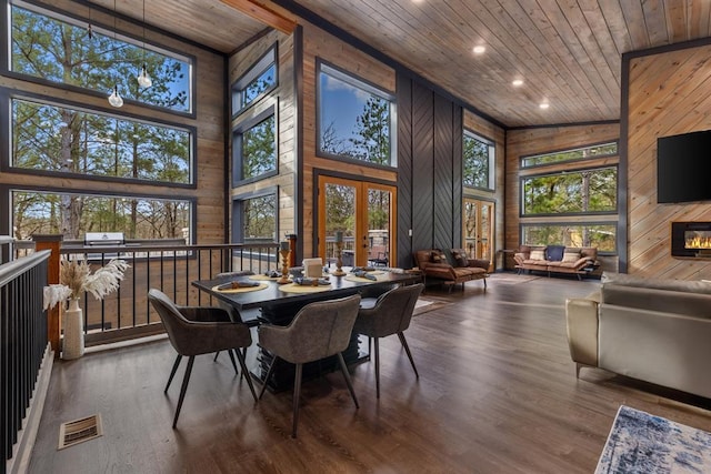 dining room with high vaulted ceiling, wood ceiling, and wooden walls