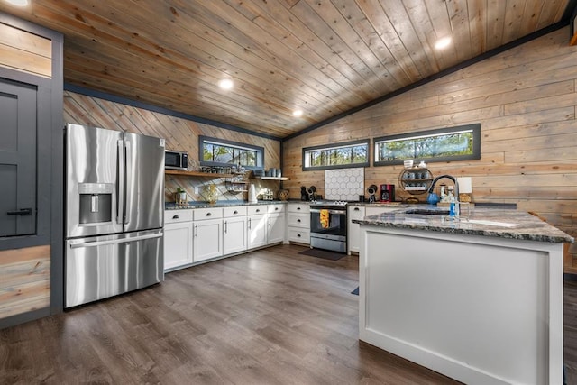 kitchen featuring vaulted ceiling, dark hardwood / wood-style floors, dark stone countertops, white cabinetry, and stainless steel appliances