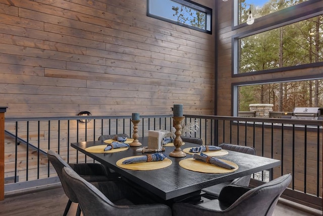 dining area featuring a high ceiling, hardwood / wood-style floors, and wooden walls