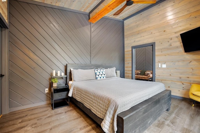 bedroom with wooden walls, wooden ceiling, ceiling fan, light hardwood / wood-style flooring, and lofted ceiling with beams