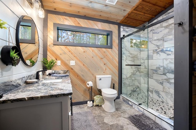 bathroom with toilet, wooden walls, a shower with shower door, and vanity