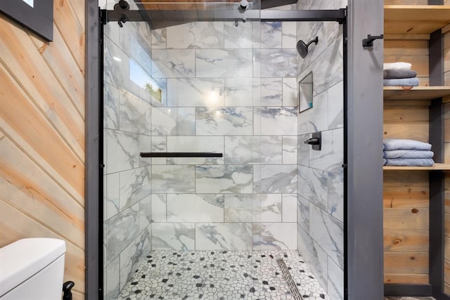 bathroom featuring an enclosed shower, wood walls, and toilet