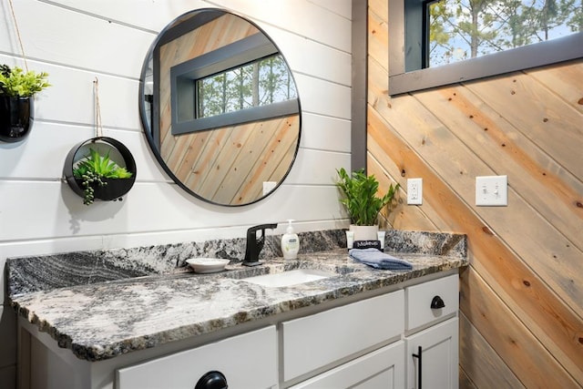 bathroom featuring vanity, a wealth of natural light, and wooden walls