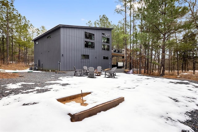 snow covered back of property featuring an outdoor fire pit