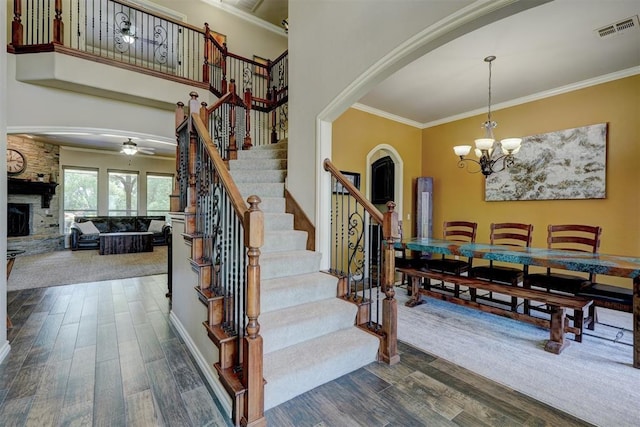 staircase featuring visible vents, arched walkways, ornamental molding, and a fireplace