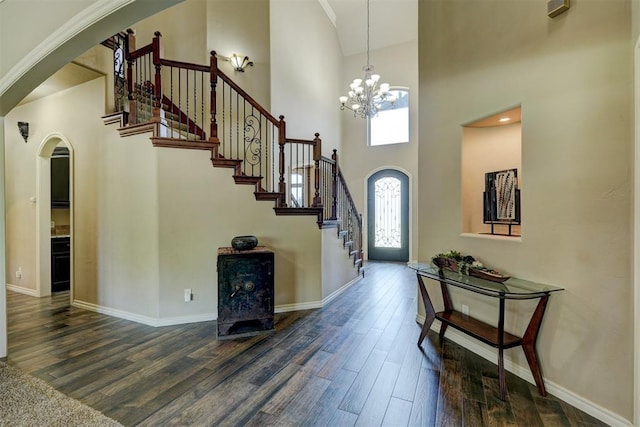 foyer entrance featuring stairway, a notable chandelier, wood finished floors, and arched walkways