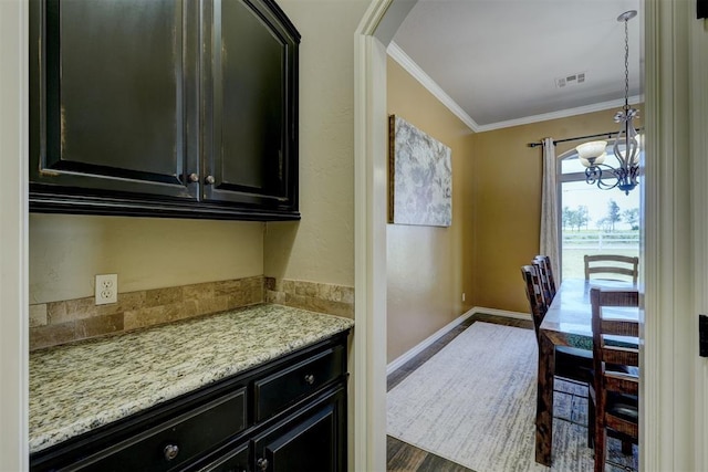 kitchen with visible vents, ornamental molding, an inviting chandelier, baseboards, and dark cabinets