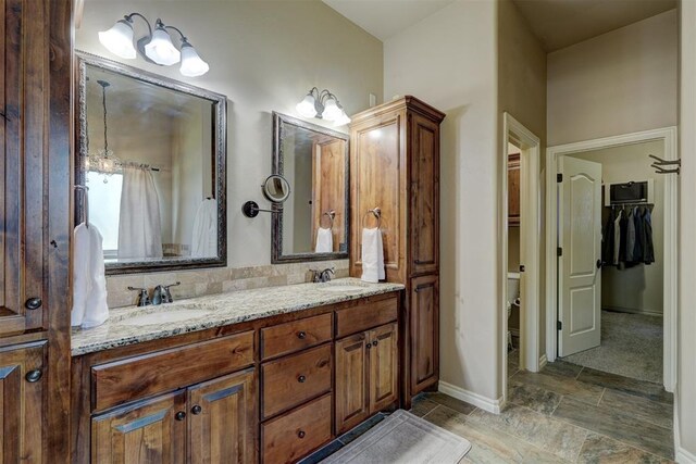 bathroom featuring a sink, baseboards, toilet, and double vanity