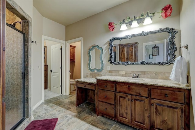 full bath featuring vanity, toilet, a stall shower, and stone finish flooring