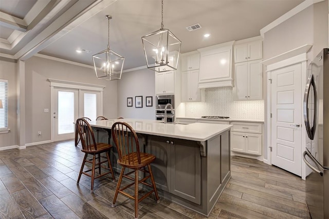 kitchen with a spacious island, a breakfast bar area, white cabinetry, decorative light fixtures, and stainless steel appliances