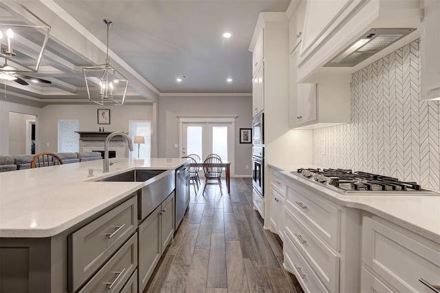 kitchen featuring white cabinetry, decorative light fixtures, stainless steel appliances, and an island with sink