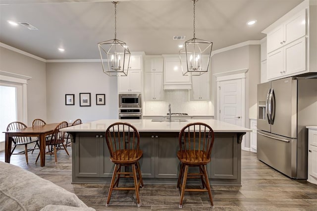 kitchen featuring a kitchen island with sink, pendant lighting, and stainless steel appliances