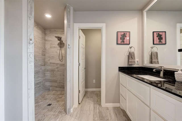 bathroom with a tile shower and vanity