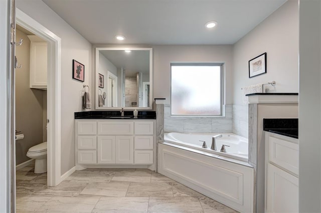 bathroom with a tub to relax in, vanity, and toilet