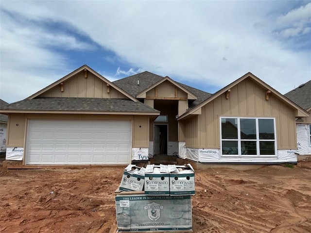 property under construction featuring a shingled roof, an attached garage, and board and batten siding