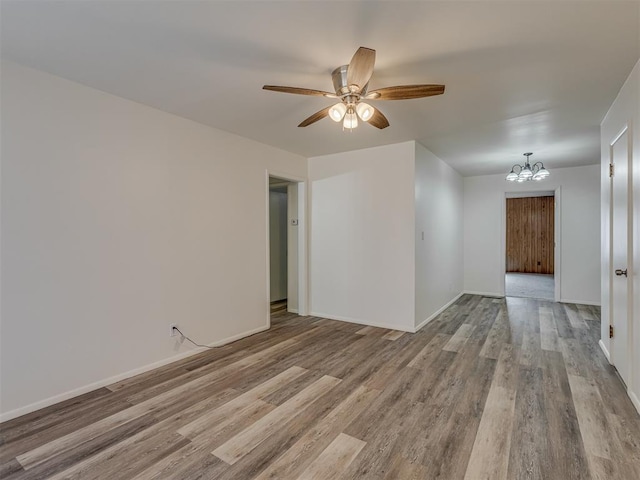 unfurnished room featuring ceiling fan with notable chandelier and light hardwood / wood-style floors