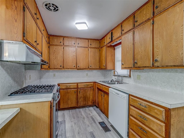 kitchen with stainless steel range with gas cooktop, tasteful backsplash, sink, white dishwasher, and light wood-type flooring