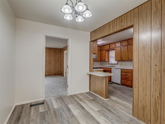 kitchen featuring tasteful backsplash, sink, a chandelier, white dishwasher, and light wood-type flooring