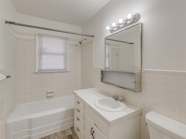 full bathroom featuring tile walls, vanity, wood-type flooring, toilet, and tiled shower / bath