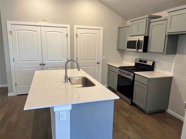 kitchen with dark wood-style floors, appliances with stainless steel finishes, vaulted ceiling, gray cabinets, and a sink