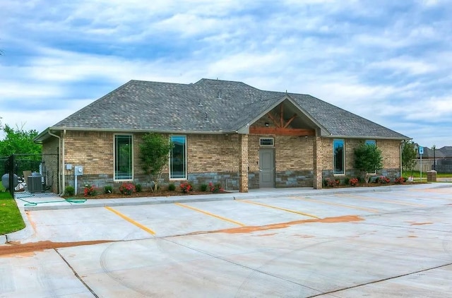 ranch-style home featuring a shingled roof, brick siding, and uncovered parking